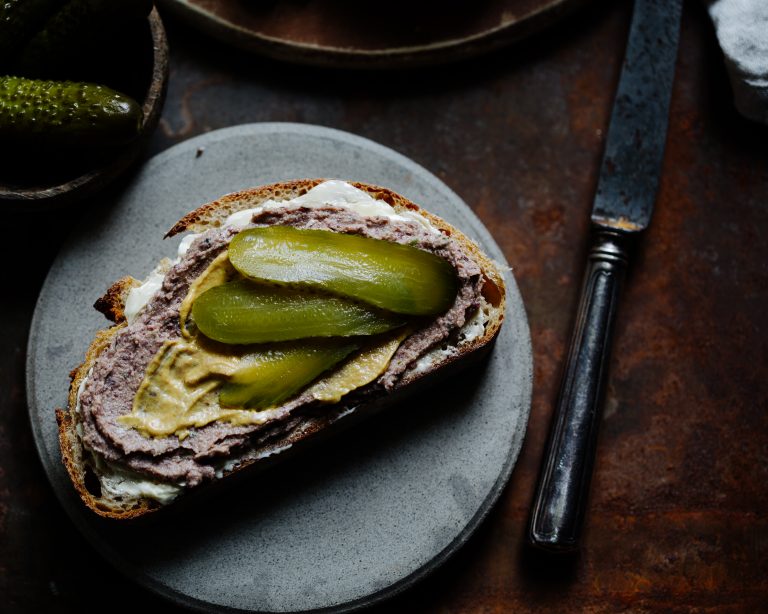 Vegane Leberwurst auf einem Stück Brot mit Gewürzgurke und Senf