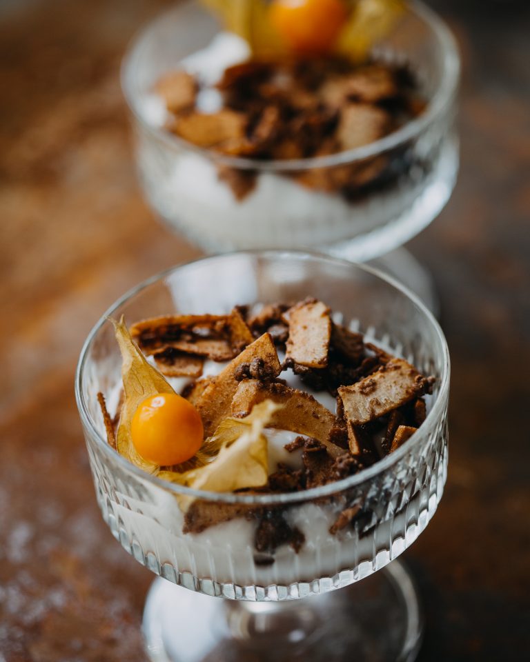 griechischer Joghurt mit karamellisierten Kokosflakes und physalis in einer Glasschale
