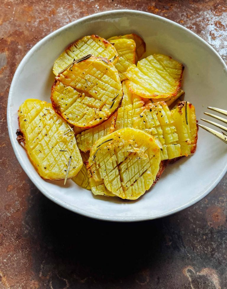 Vegane Crunchy Potatoes. Ein leckerer veganer Snack. Kartoffeln im Ofen gebacken in einer hellen Schale mit rostigem Hintergrund