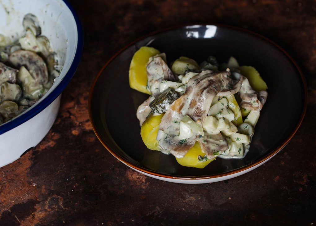 Veganer-Matjes-Heringssalat-Rezept-theveganloversclub. Nach Hausfrauenart. Salat mit Salzkartoffeln auf einem dunklen Steingutteller.