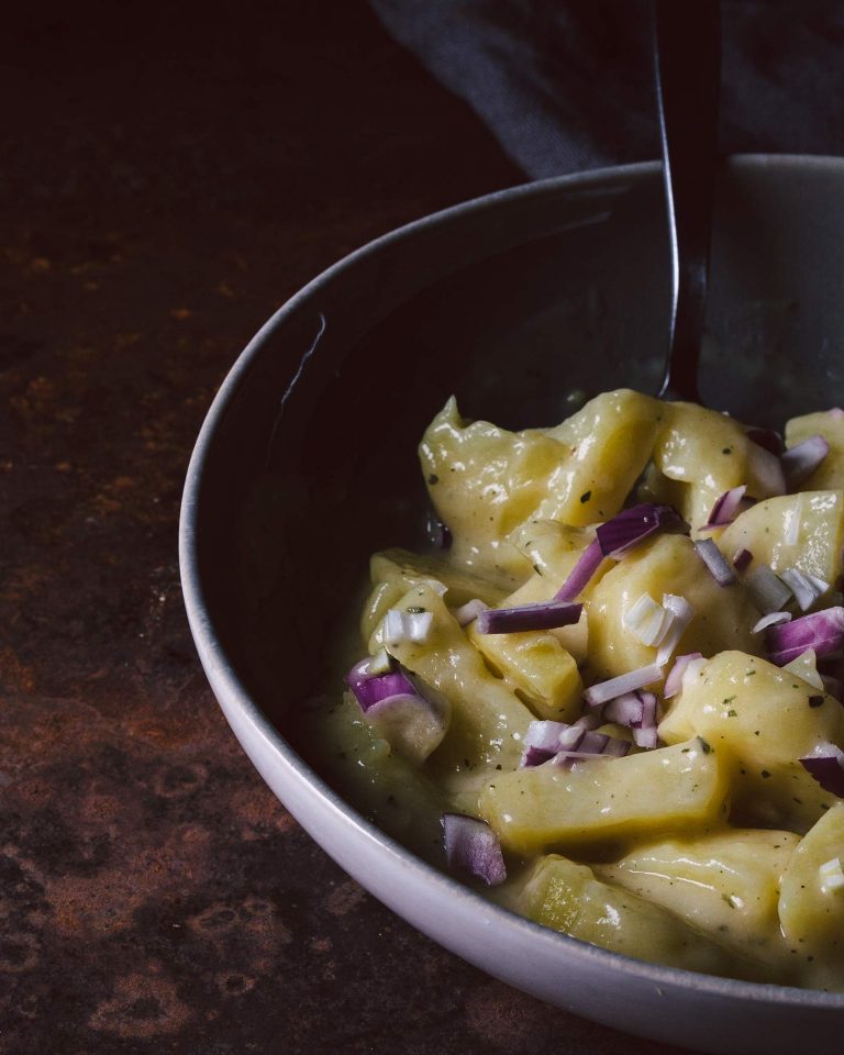 Veganer Kartoffelsalat mit roten Zwiebeln in Schüssel, serviert als klassische Grillbeilage