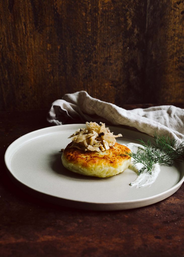 Goldbraun gebratene vegane Kartoffelkuchen mit Sauerkraut-Pilz-Füllung und frischem Dill-Dip