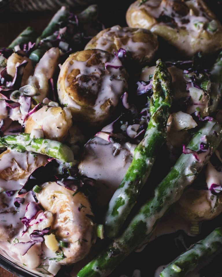 Veganer Kartoffelsalat mit Ofenkartoffeln und grünem Spargel auf Teller serviert