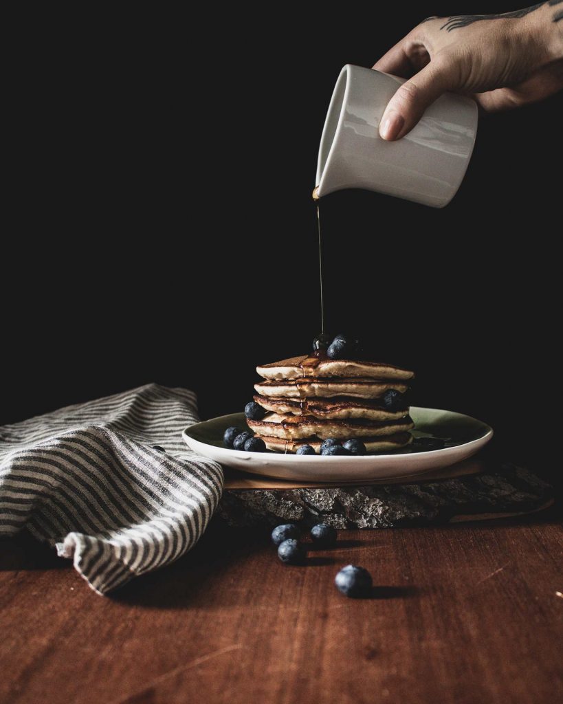 Fluffige vegane Banane Blaubeere Pancakes, gestapelt und mit Ahornsirup sowie frischen Blaubeeren serviert