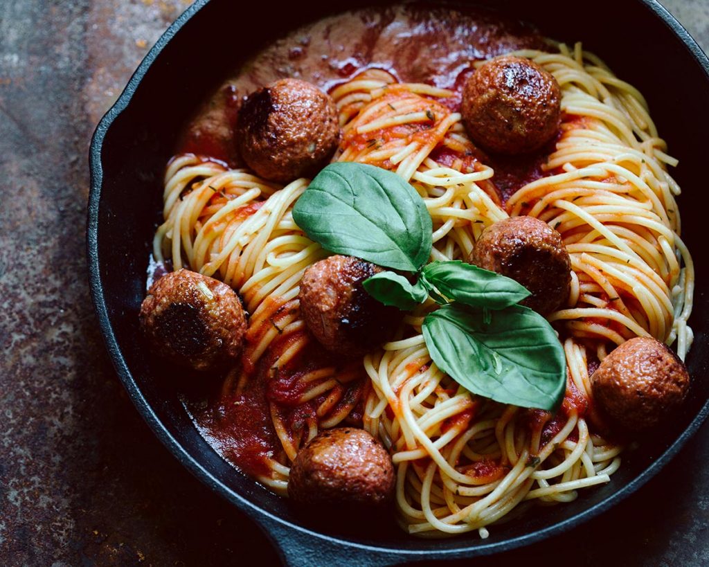 Vegane Meatballs mit Spaghetti in pikanter Tomatensauce auf Teller serviert