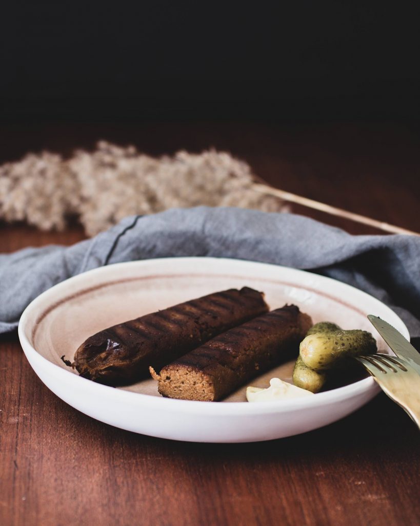 Hausgemachte vegane Bratwurst aus Seitan, angebraten in Pfanne