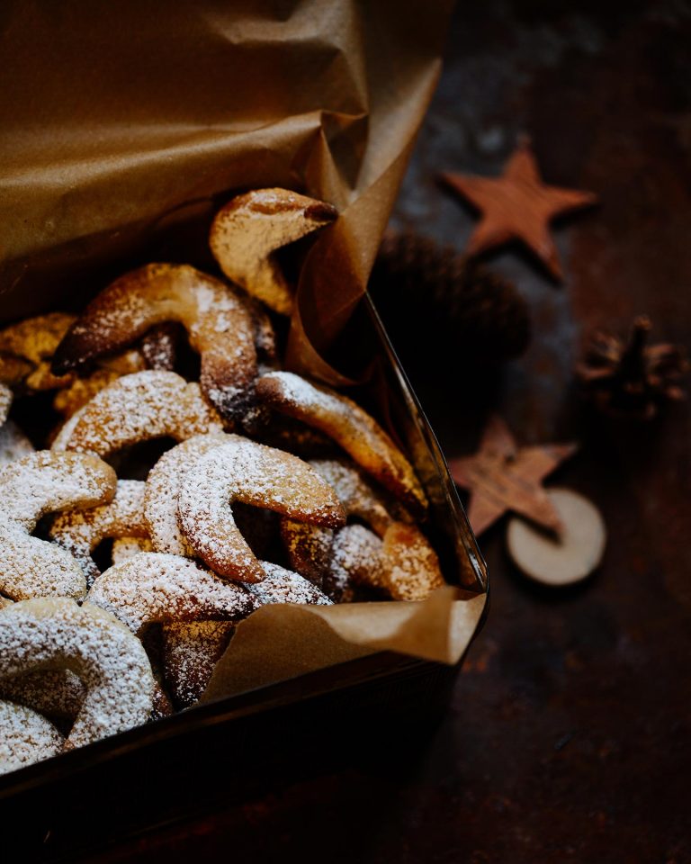 Vegane Vanillekipferl auf Backpapier mit Puderzucker bestäubt