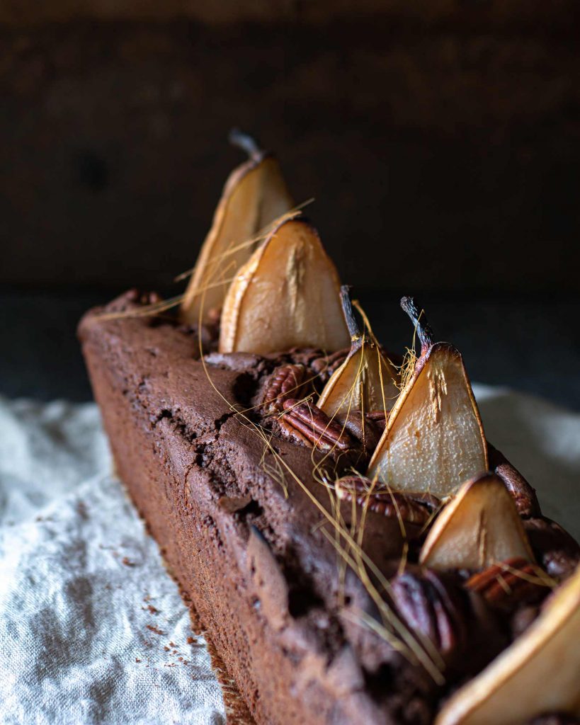 Veganer Schokokuchen mit versunkenen Birnen in einer Kastenform, saftig und mit Pekannüssen